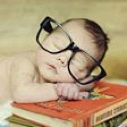 baby asleep atop stack of books.glasses